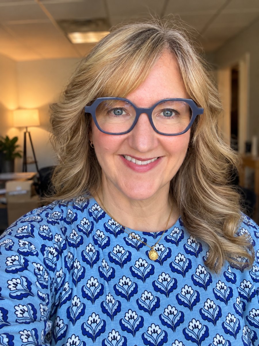 Justine Bassett, smiling, in a warm office